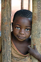 Pygmy child in front of a mud hut